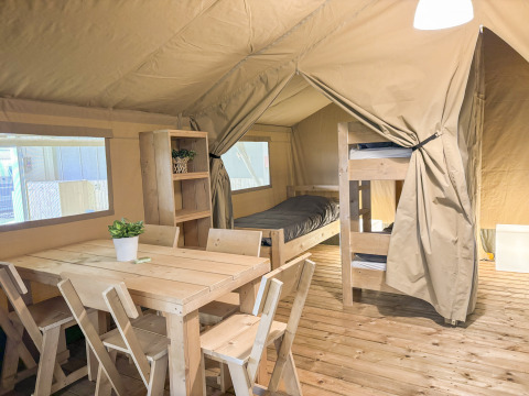 Interno di una tenda safari all'Himmerland Camping in Danimarca, con mobili in legno e letti a castello.