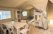 Interior de una carpa safari en Himmerland Camping, Dinamarca, con muebles de madera y literas.