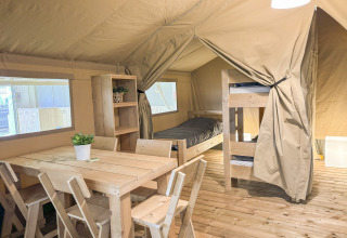 Innenraum eines gemütlichen Safarizelts auf Himmerland Camping mit Holzmöbeln und Etagenbett.