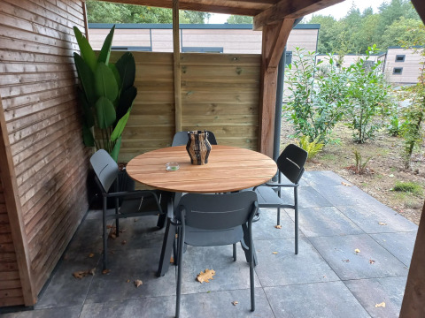 Terraza cubierta en Tiny Borg, Vakantiepark De Wiltzangh, Países Bajos, con mesa redonda y cuatro sillas.