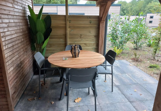 Patio coperto al Tiny Borg, Vakantiepark De Wiltzangh, Paesi Bassi, con tavolo rotondo e quattro sedie.