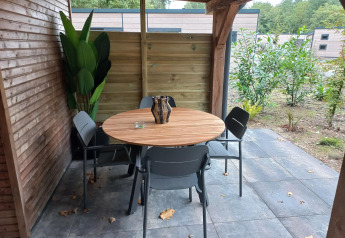 Covered patio at Tiny Borg, Vakantiepark De Wiltzangh, Netherlands, with round wooden table and four chairs.