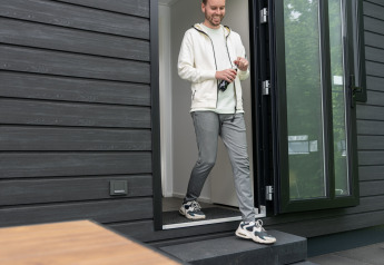 Man stepping out of Sunlodge at Holiday Park 't Rheezerwold, sunglasses seen on a wooden table in front.