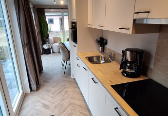 Moderne køkkenudsigt i Groeneborg lodge med trægulv og store vinduer på Vakantiepark De Wiltzangh.