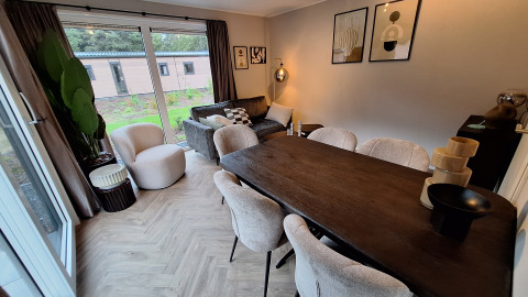 Zona soggiorno e pranzo moderna presso Groeneborg lodge con grandi finestre al Vakantiepark De Wiltzangh, Paesi Bassi.