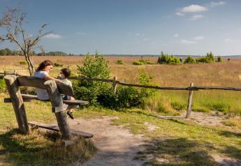 Una donna e un bambino seduti su una panchina al Groeneborg lodge con Hottub, immersi nella natura.
