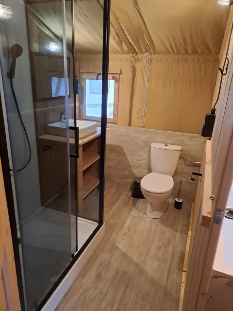 Salle de bain dans une tente safari avec douche, toilettes et lavabo au Camping de Regenboog, République Tchèque.
