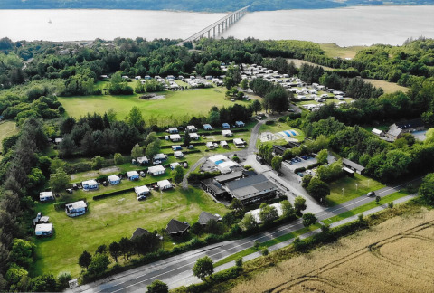 Aerial view of Glyngore Camping holiday park in Central Denmark Region, showing campers, greenery and a bridge.