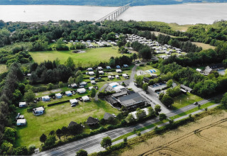Aerial view of Glyngore Camping holiday park in Central Denmark Region, showing campers, greenery and a bridge.