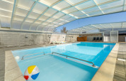 Piscine intérieure avec toit transparent, transats et ballon de plage au Glyngore Camping au Danemark.