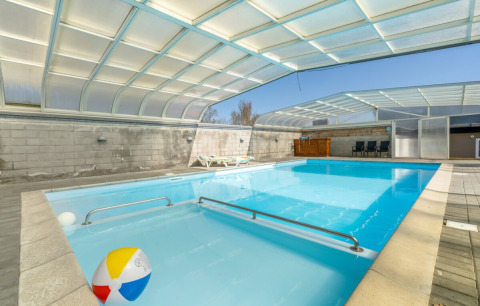 Indendørs swimmingpool med gennemsigtigt tag, liggestole og farverig badebold på Glyngore Camping i Danmark.