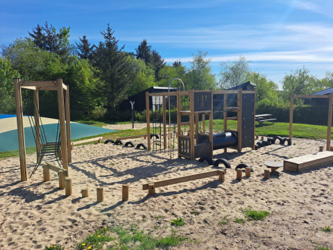 Playground with climbing frames and sand at Glyngore Camping in Central Denmark Region on a sunny day.