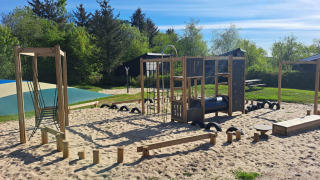 Playground with climbing frames and sand at Glyngore Camping in Central Denmark Region on a sunny day.