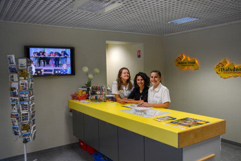 Receptie van vakantiepark La Draille in Occitanië, Frankrijk met glimlachend personeel achter balie.