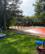 Parque infantil con balancín, tiovivo, almohada inflable y juego de escalar en Himmerland camping, Dinamarca.