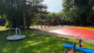 Playground featuring seesaw, roundabout, bouncy pillow and climbing structure at Himmerland camping, Denmark.