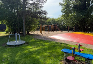 Aire de jeux avec balançoire, manège, coussin gonflable et structure d’escalade à Himmerland camping, Danemark.