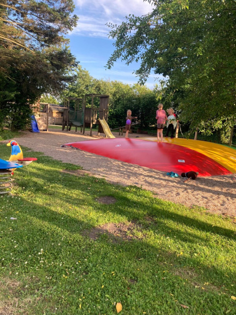 Niños juegan sobre un cojín saltarín rojo y parque infantil en Himmerland Camping, Jutlandia del Norte, Dinamarca.