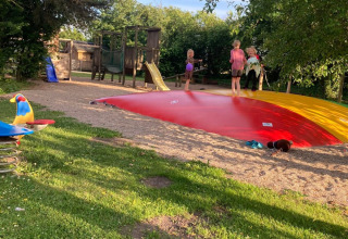 Niños juegan sobre un cojín saltarín rojo y parque infantil en Himmerland Camping, Jutlandia del Norte, Dinamarca.