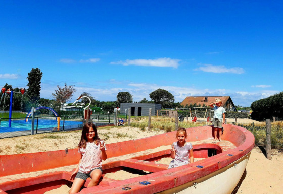 Kinderen spelen in een oude reddingsboot op de speeltuin van Kompas Camping Westende in West-Vlaanderen.