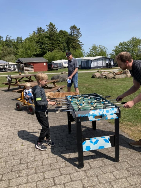Kinder und Erwachsene spielen Tischfußball im Freien auf dem Himmerland Campingplatz in Nordjütland.