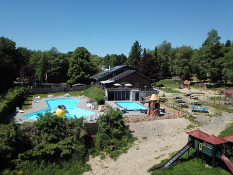 Luftaufnahme von Pool, Spielplatz und Picknicktischen im Ferienpark Petite Suisse in Belgien Luxemburg.