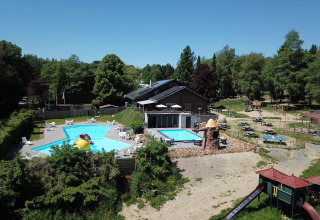 Luchtfoto van zwembaden, speeltuin en picknicktafels bij vakantiepark Petite Suisse in Belgisch Luxemburg.