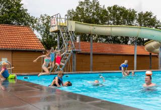 Kinderen springen in een buitenzwembad bij De Tien Heugten vakantiepark in Drenthe, Nederland.