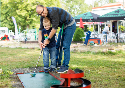 Vader en zoon spelen samen minigolf buiten bij vakantiepark De Tien Heugten in Drenthe, Nederland.