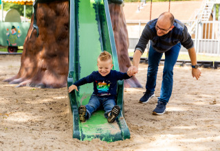 Vader en zoon genieten samen op de glijbaan op een speeltuin in De Tien Heugten, Drenthe, Nederland.
