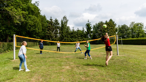 Vakantiegangers spelen volleybal op een grasveld bij De Tien Heugten, een vakantiepark in Drenthe.