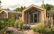 Modernes Tiny House 'Tiny Lodge' mit Whirlpool im Veluwepark de Bosgraaf, umgeben von Natur in den Niederlanden.