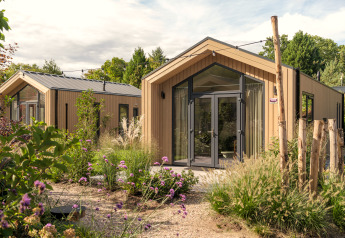 Moderne tiny house ‘Tiny Lodge’ met hottub op Veluwepark de Bosgraaf, omringd door planten in Nederland.