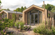 Tiny house moderne 'Tiny Lodge' avec jacuzzi au Veluwepark de Bosgraaf, entourée de plantes aux Pays-Bas.