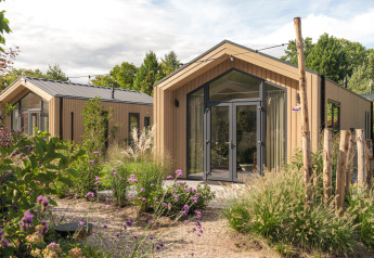 Moderne tiny house ‘Tiny Lodge’ met hot tub bij Veluwepark de Bosgraaf, omringd door groen in Nederland.