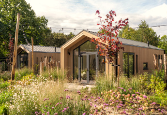 Tiny Lodge: Modernes Tiny House mit Holzverkleidung, umgeben von üppigem Garten und Wildblumen.