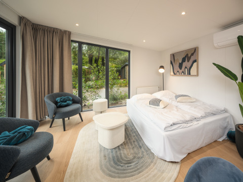 Moderne lodge soveværelse med store vinduer, dobbeltseng og stilfuld indretning i Zypendaal Comfort.