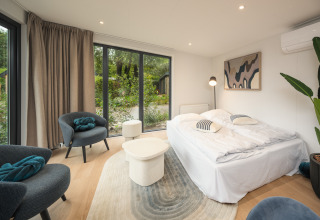 Moderne lodge soveværelse med store vinduer, dobbeltseng og stilfuld indretning i Zypendaal Comfort.