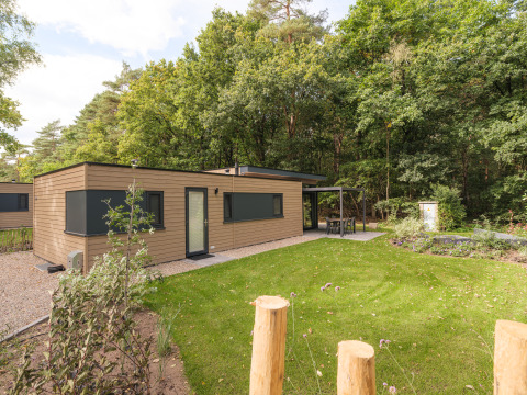 Cannenburch Deluxe-lodge bij Veluwepark de Bosgraaf in Nederland met overdekt terras en groene tuin.