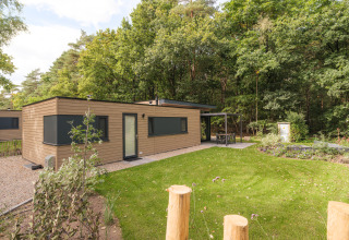 Cannenburch Deluxe-lodge bij Veluwepark de Bosgraaf in Nederland met overdekt terras en groene tuin.