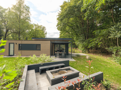 Moderne Cannenburch Deluxe lodge bij Veluwepark de Bosgraaf in Nederland met terras en buitenvuurplek.