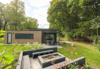 Moderna cabaña Cannenburch Deluxe en Veluwepark de Bosgraaf, Países Bajos, con patio y zona de hoguera exterior.