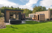 Moderno lodge Essenburgh con vasca idromassaggio e sauna al Veluwepark de Bosgraaf, Paesi Bassi, immerso nel verde.