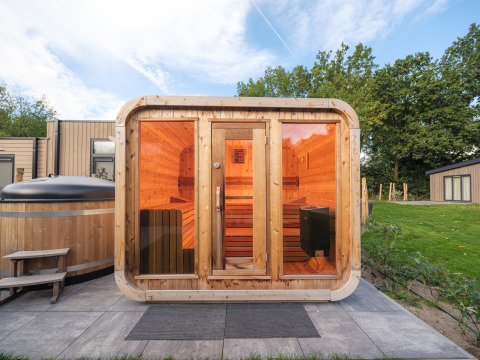 Sauna e vasca idromassaggio all'aperto in un lodge del Veluwepark de Bosgraaf, Paesi Bassi, immersi nel verde.
