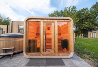 Sauna e vasca idromassaggio all'aperto in un lodge del Veluwepark de Bosgraaf, Paesi Bassi, immersi nel verde.