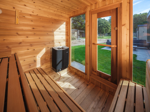 Vista interna di una sauna in legno con panche e grandi finestre a Veluwepark de Bosgraaf, Paesi Bassi.