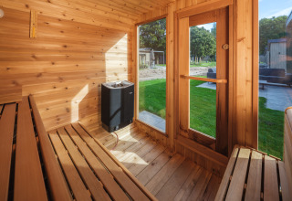 Vista interna di una sauna in legno con panche e grandi finestre a Veluwepark de Bosgraaf, Paesi Bassi.