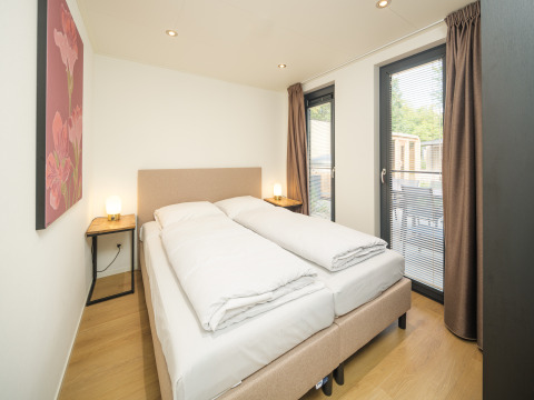 Dormitorio moderno en la cabaña Essenburgh con bañera de hidromasaje y sauna en Veluwepark de Bosgraaf, Países Bajos.