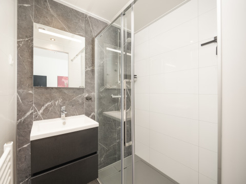 Baño moderno en la cabaña Essenburgh con ducha de vidrio y lavabo, en Veluwepark de Bosgraaf, Países Bajos.