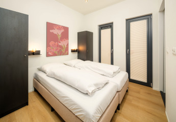Modernes Schlafzimmer in der Essenburgh Lodge mit Doppelbett, stilvollem Dekor und heller Einrichtung im Veluwepark de Bosgraaf, Niederlande.